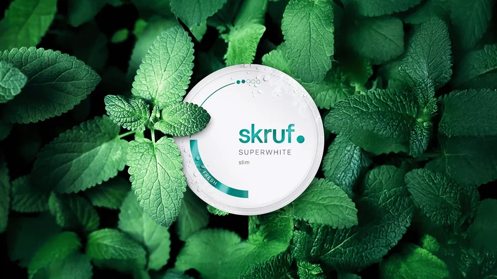 Website-Relaunch für skruf: Eine weiße Dose skruf Superwhite mit Wassertropfen liegt eingebettet in frischen, grünen Minzblättern.