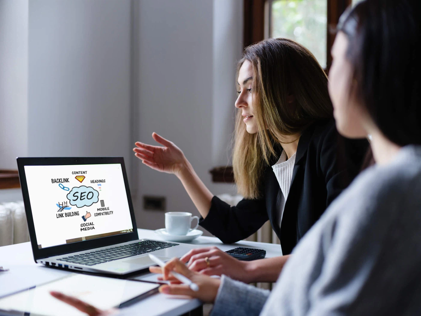 Suchmaschinenoptimierung für KI-Overviews: Eine Expertin der MMCAGENTUR erklärt eine SEO-Strategie am Laptop, um Websites zukunftssicher zu optimieren.
