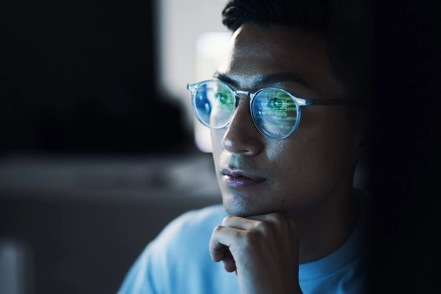 Moderne Headless CMS Webentwicklung: Ein Programmierer blickt fokussiert auf den Bildschirm mit grün gespiegeltem Programmcode für schnelle Ladezeiten und Performance.