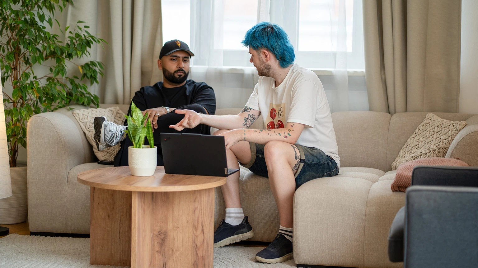 Digital Marketing Buddy Beratung bei MMCAGENTUR: Ishan und Flo besprechen am Sofa im hellen Agenturbüro eine konkrete Aufgabe am Laptop.
