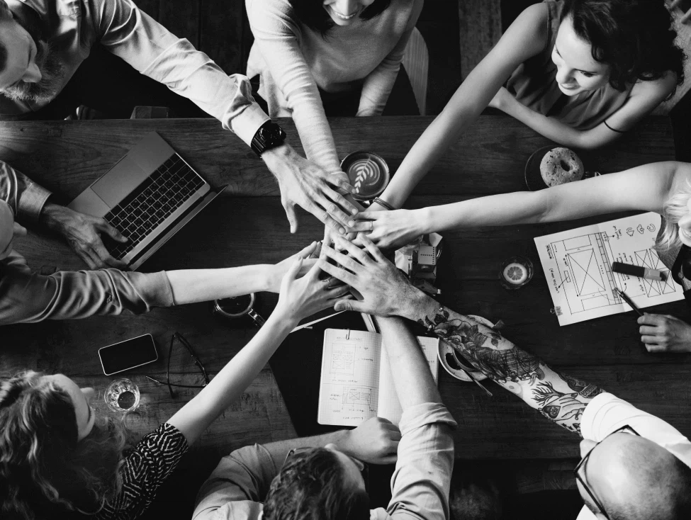 Mehrere Hände liegen als Teamgeste übereinander.