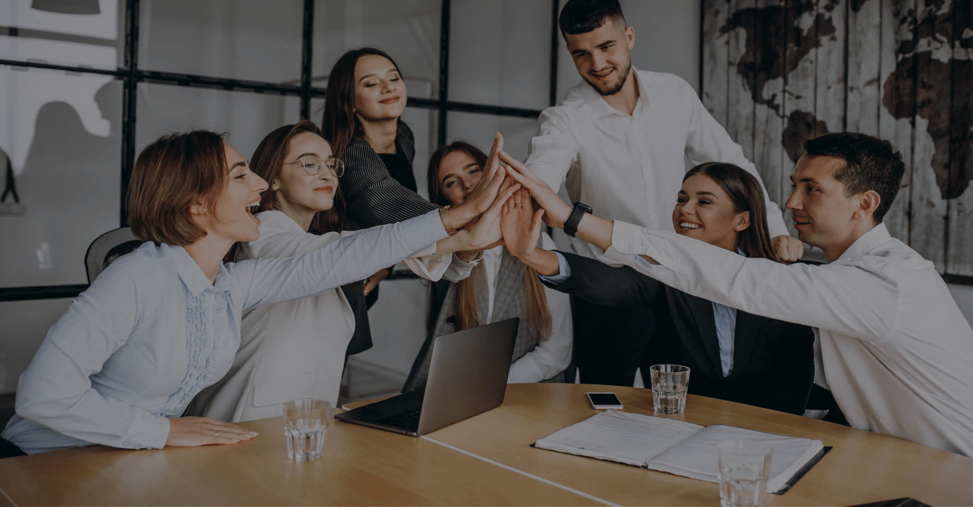 Flexibler Support durch den Digital Marketing Buddy (DMB): Ein motiviertes Team der MMCAGENTUR klatscht am Besprechungstisch zu einem High-Five ab.