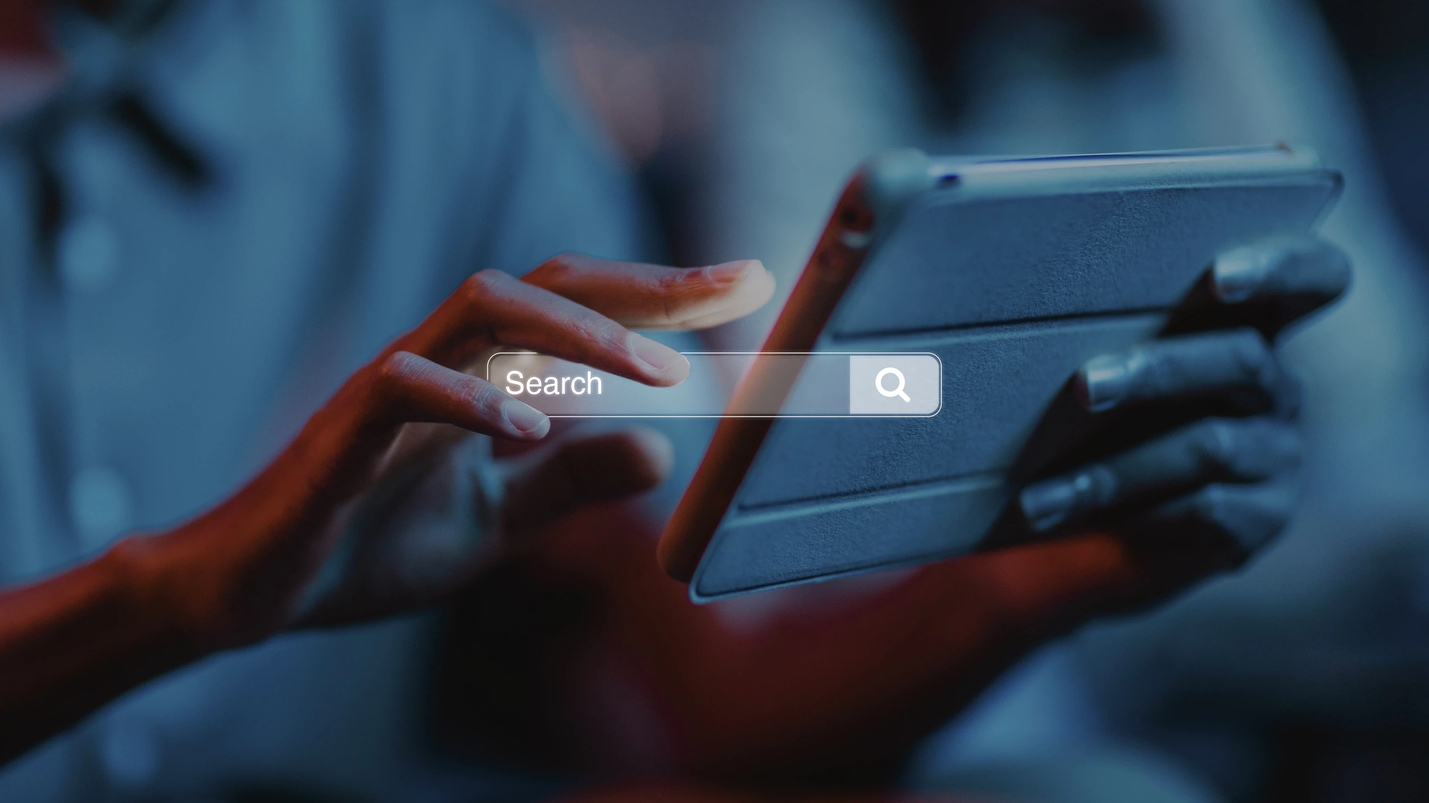Suchmaschinenoptimierung und digitale Recherche: Eine Person nutzt ein Tablet mit eingeblendeter Suchleiste.