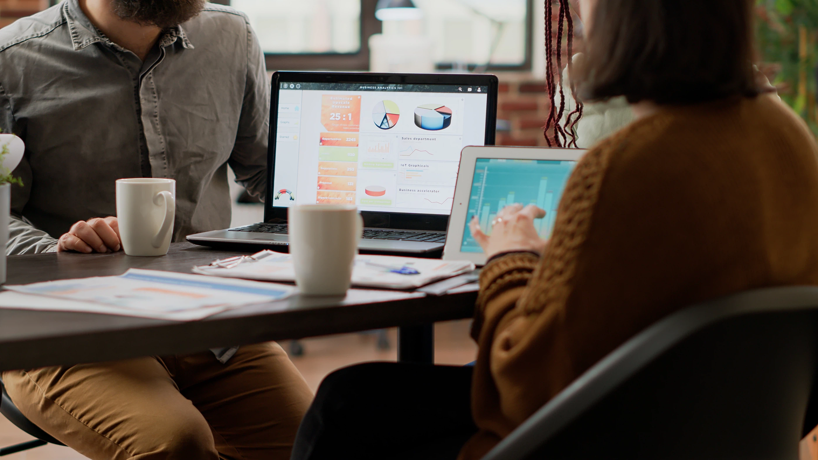 Business Analytics und Datenanalyse im Team: Mehrere Personen besprechen Diagramme und Kennzahlen auf Laptop und Tablet.