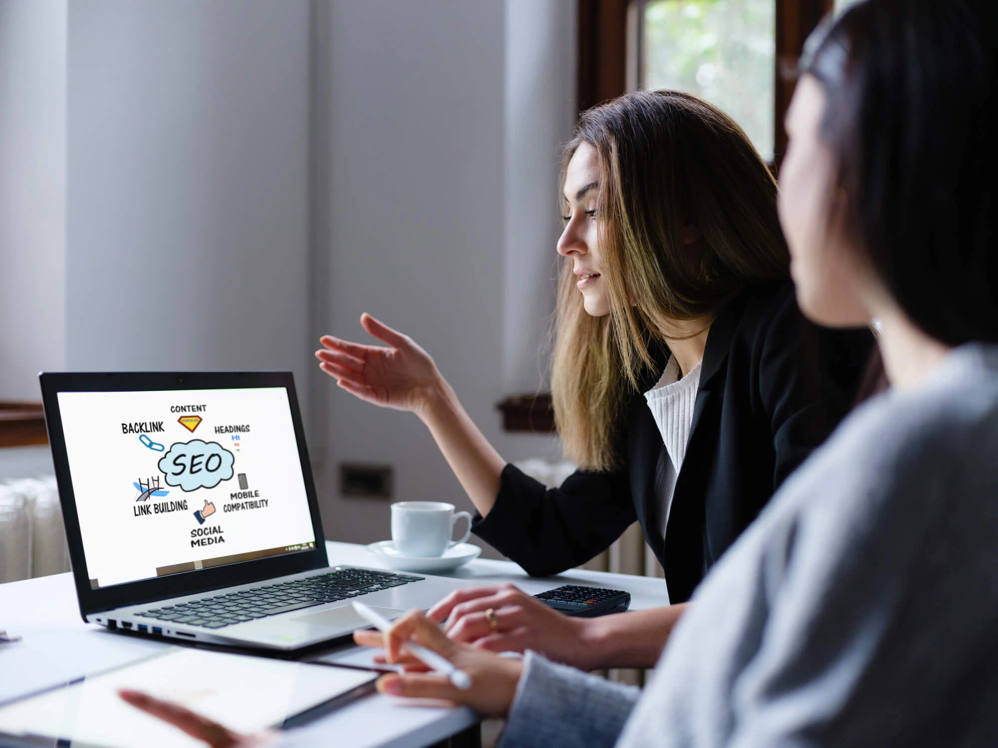 Suchmaschinenoptimierung für KI-Overviews: Eine Expertin der MMCAGENTUR erklärt eine SEO-Strategie am Laptop, um Websites zukunftssicher zu optimieren.