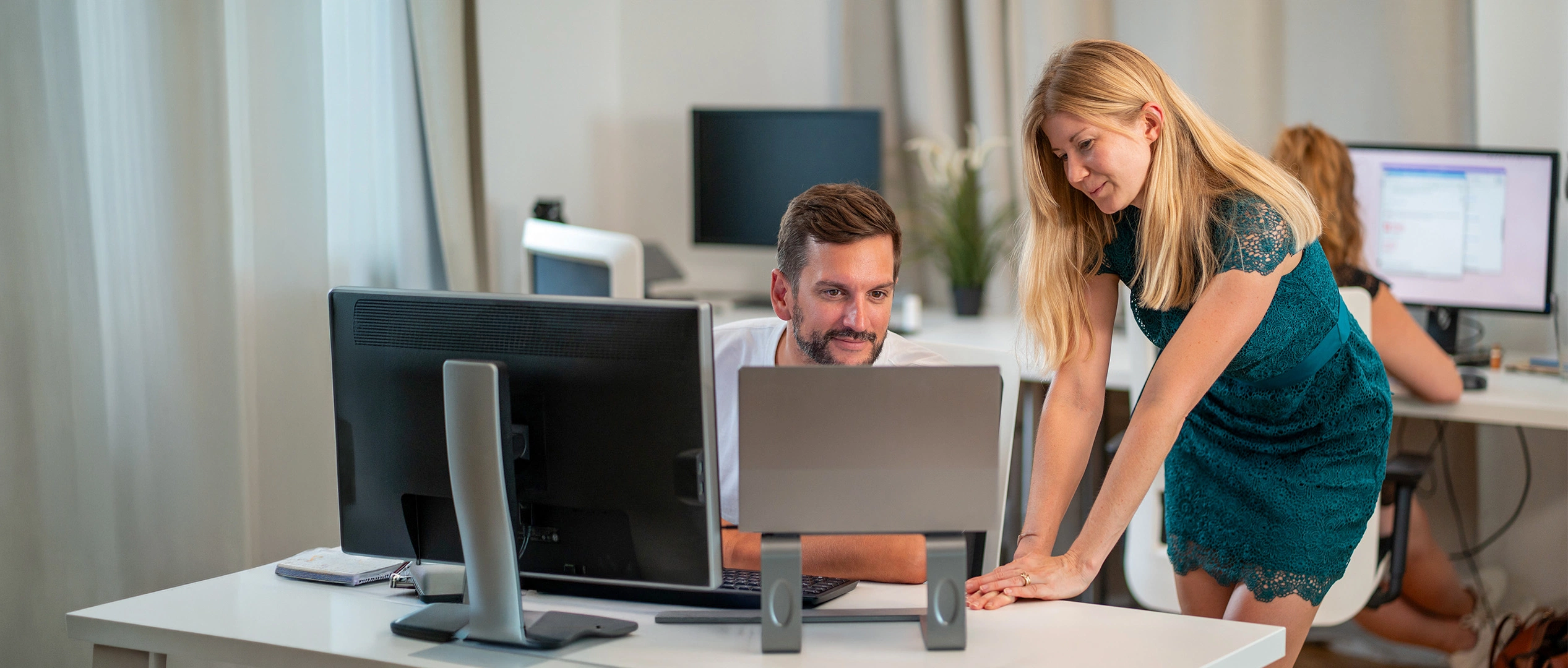 Marketing-Workshop der MMCAGENTUR: Zwei Kolleg:innen arbeiten gemeinsam an einem Arbeitsplatz im hellen Agenturbüro.