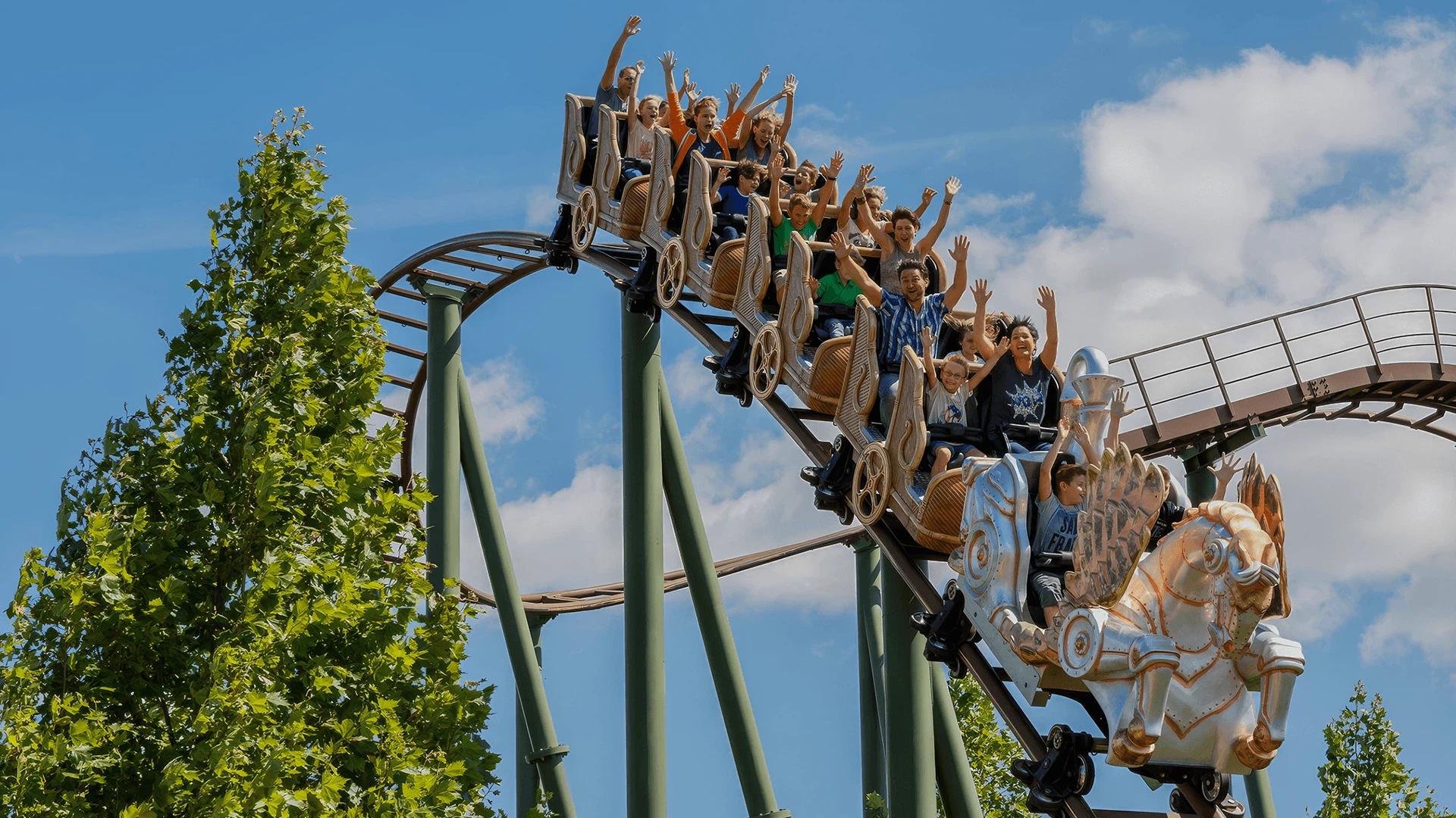 Paid-Social-Strategie für Familypark von der MMCAgentur: Familien und Kinder fahren bei blauem Himmel mit erhobenen Händen auf einer Achterbahn im Familypark.