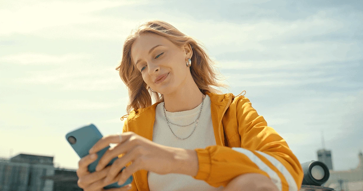 Social Media und Short-Form-Video: Eine junge Frau scrollt im Freien am Smartphone durch Trends auf TikTok, Instagram und YouTube.