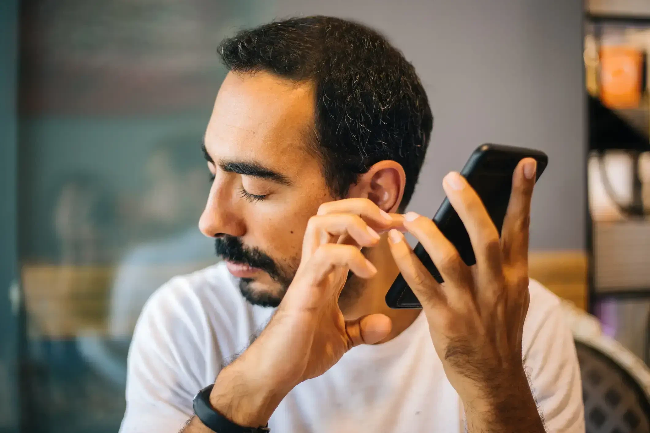Barrierefreies Webdesign im Fokus: Ein blinder Mann nutzt die Sprachausgabe und den Screenreader seines Smartphones bei geschlossenen Augen.