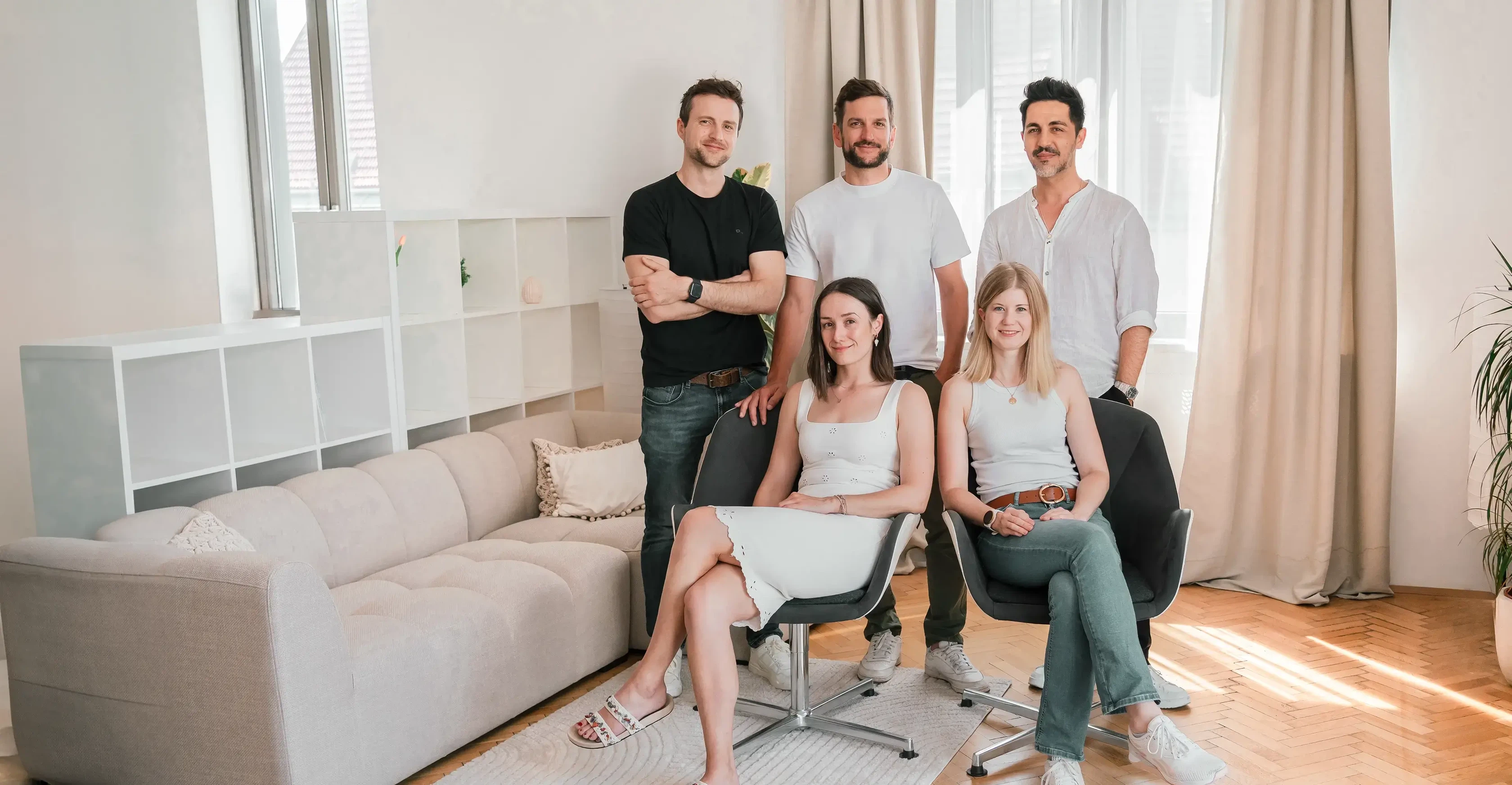 Das Team der MMC Agentur: Fünf Mitarbeiterinnen und Mitarbeiter blicken lächelnd und nahbar in einem hellen, modernen Büro in die Kamera.